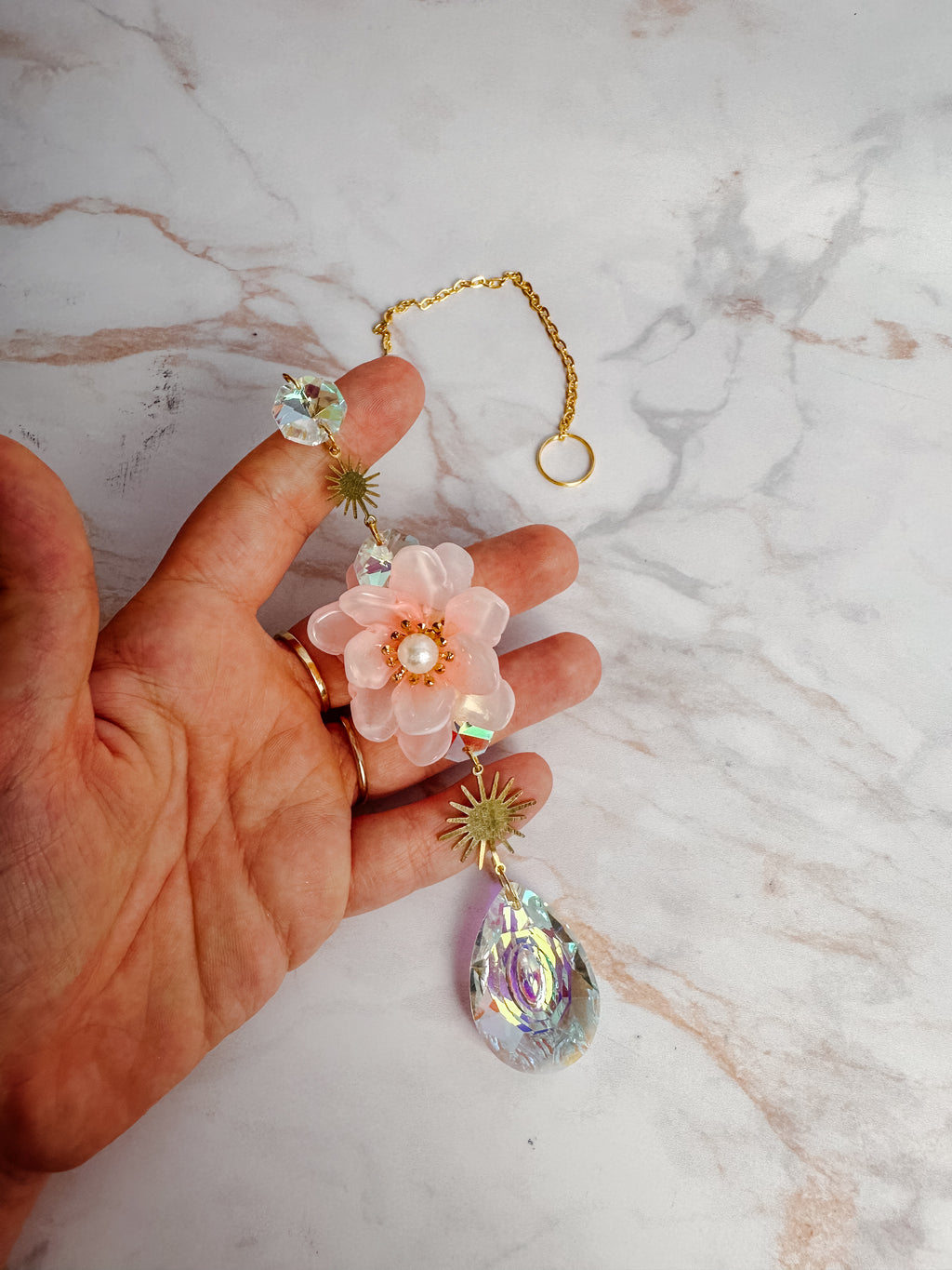 Détail d’un attrape-soleil fleur rose avec perles irisées et cristal