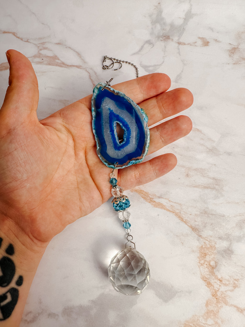 Détail d’un attrape-soleil en agate bleue avec perles bleues et boule facettée