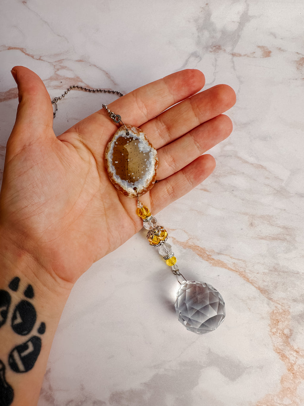 Détail d’un attrape-soleil en agate naturelle aux tons miel avec cristal suspendu